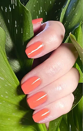 Mano de mujer con las uñas coral Arrecife naturales y brillantes del esmalte de uñas sin tóxicos de Mother Nailture