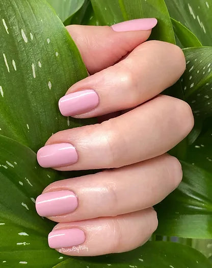 Mano de mujer con las uñas rosas Flor de Cerezo naturales y brillantes del esmalte de uñas sin tóxicos de Mother Nailture