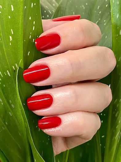 Mano de mujer con las uñas rojas Pasión naturales y brillantes del esmalte de uñas sin tóxicos de Mother Nailture