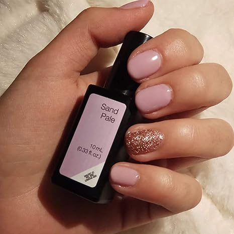 Mano con uñas rosas Sand Pale sujetando frasco de esmalte de gel para uñas semipermanentes de Sensationail