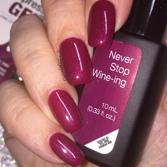 Mano con uñas burdeos Never Stop Wine-ing sujetando frasco de esmalte de gel para uñas semipermanentes