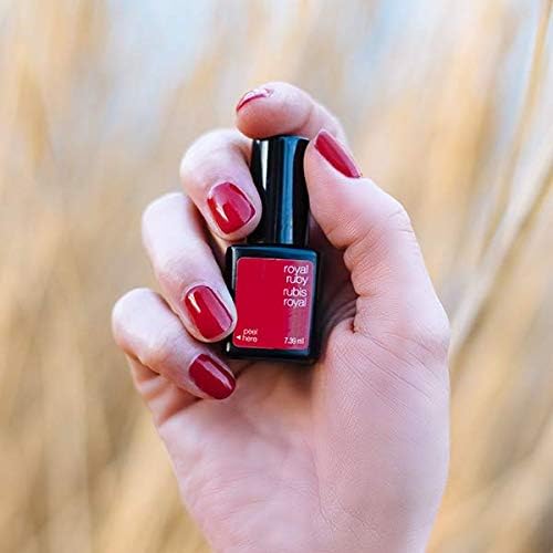 Mano con uñas rojas Royal Ruby sujetando frasco de esmalte de gel para uñas semipermanentes
