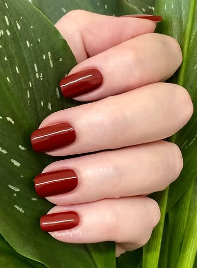 Mano de mujer con las uñas rojas Rubí naturales y brillantes del esmalte de uñas sin tóxicos de Mother Nailture