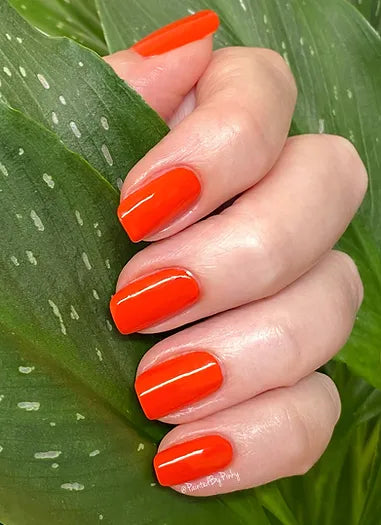 Mano de mujer con las uñas rojas naturales y brillantes del esmalte de uñas sin tóxicos de Mother Nailture