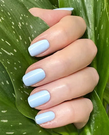 Mano de mujer con las uñas azules Azul Islandia naturales y brillantes del esmalte de uñas sin tóxicos de Mother Nailture