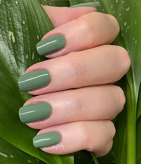 Mano de mujer con las uñas verdes Nailture Green naturales y brillantes del esmalte de uñas sin tóxicos de Mother Nailture