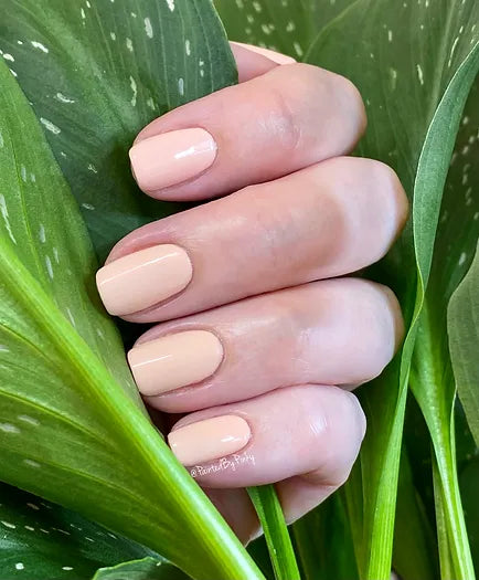 Mano de mujer con las uñas nude Moody Nude naturales y brillantes del esmalte de uñas sin tóxicos de Mother Nailture