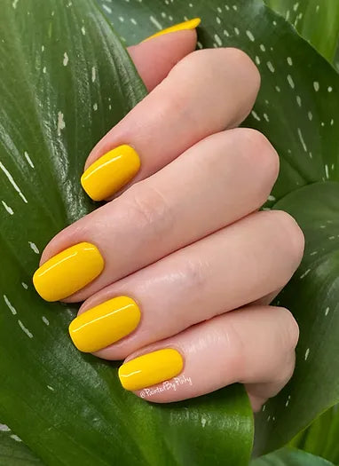 Mano de mujer con las uñas amarillas Buttercup naturales y brillantes del esmalte de uñas sin tóxicos de Mother Nailture