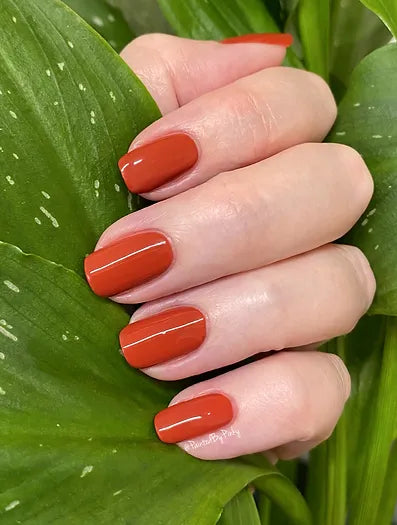 Mano de mujer con las uñas rojas Red Berry naturales y brillantes del esmalte de uñas sin tóxicos de Mother Nailture