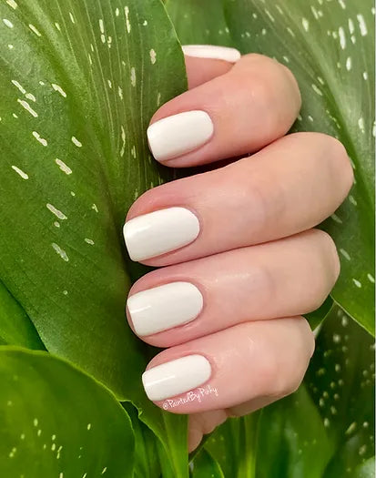 Mano de mujer con las uñas blancas Polar naturales y brillantes del esmalte de uñas sin tóxicos de Mother Nailture
