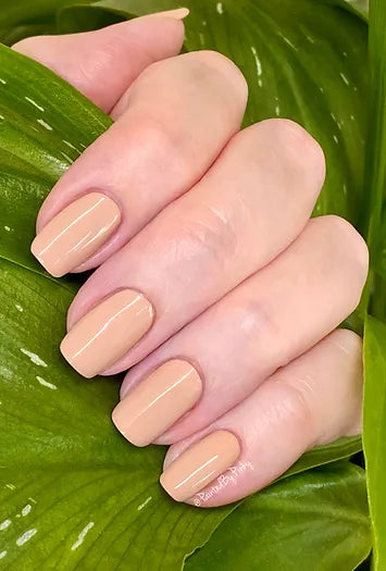 Mano de mujer con las uñas nude, naturales y brillantes del esmalte de uñas sin tóxicos de Mother Nailture