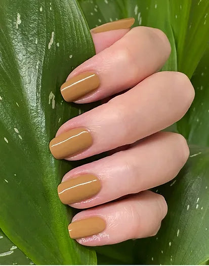 Mano de mujer con las uñas beige Sand Dune naturales y brillantes del esmalte de uñas sin tóxicos de Mother Nailture