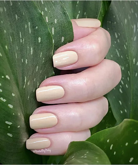 Mano de mujer con las uñas nude naturales y brillantes del esmalte de uñas sin tóxicos de Mother Nailture