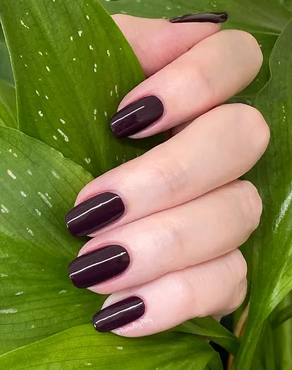 Mano de mujer con las uñas púrpura modelo Purple Rain naturales y brillantes del esmalte de uñas sin tóxicos de Mother Nailture