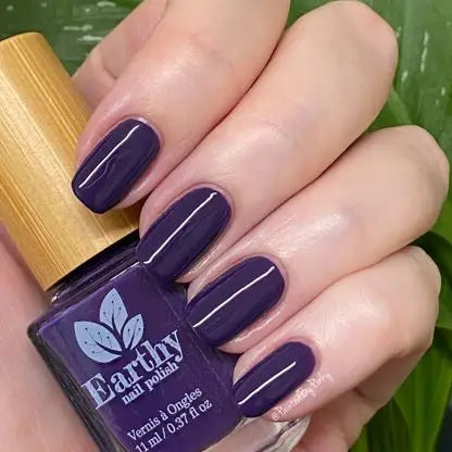 Mano de mujer con las uñas azules lavanda sujetando el frasco del esmalte de uñas sin tóxicos Jacaranda de Mother Nailture