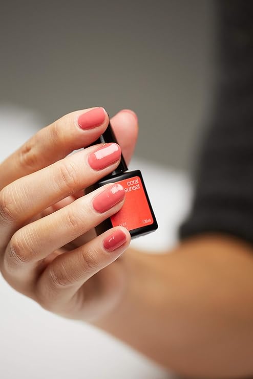 Mano con uñas Coral Sunset sujetando frasco de esmalte de gel para uñas semipermanentes