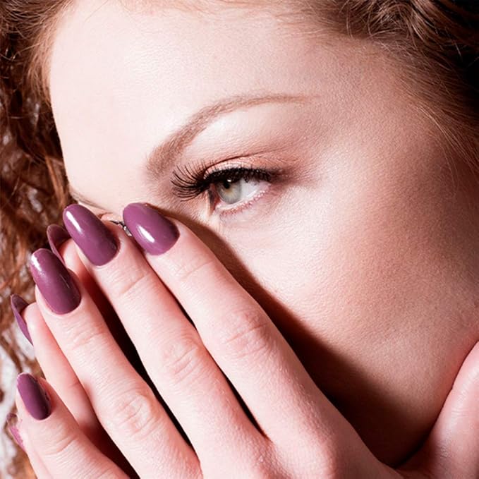 Mano con uñas burdeos Raisin The Limit del esmalte de gel para uñas semipermanentes tapandose la nariz de una mujer