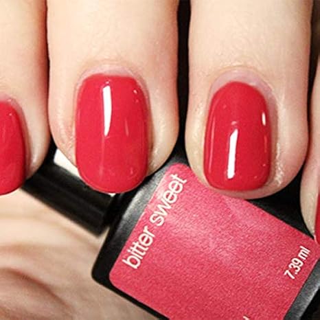 Mano con uñas rosas anaranjado brillante Bitter Sweet sujetando frasco de esmalte de gel para uñas semipermanentes