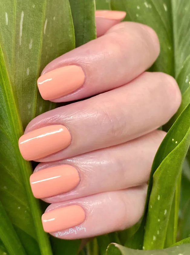Mano de mujer con las uñas rosas, naturales y brillantes del esmalte de uñas sin tóxicos de Mother Nailture